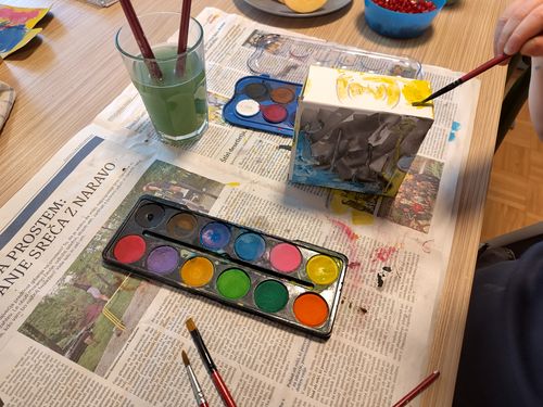 A kid is using watercolors to paint the box